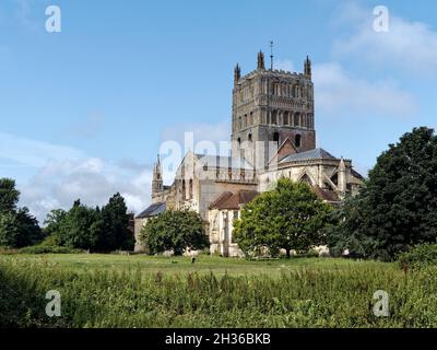 La chiesa abbaziale di St Mary the Virgin, Tewkesbury, comunemente conosciuta come l'abbazia di Tewkesbury, vista attraverso i prati d'acqua, una scena senza tempo. Foto Stock