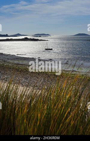 Dune di sabbia, spiaggia e barca guardando verso le isole orientali su St Martins , Isole di Scilly, Inghilterra Foto Stock