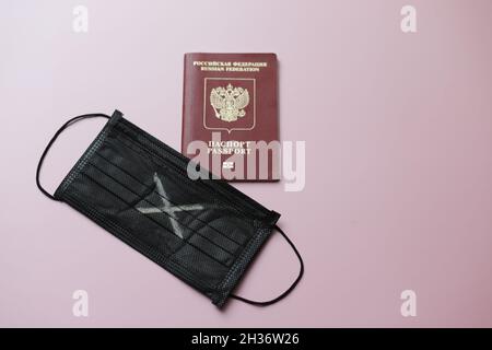 Maschera nera con croce bianca e passaporto russo per viaggiare. Foto di alta qualità Foto Stock