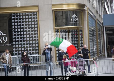 Giovane spettatore con la famiglia ondeggia una grande bandiera italiana in attesa della Columbus Day Parade per raggiungerli sulla 5th Avenue nel centro di Manhattan. Foto Stock