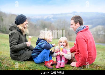 Una famiglia con gelati di Winstones Ice Cream su Rodborough Common a Stroud, Gloucestershire. Foto Stock