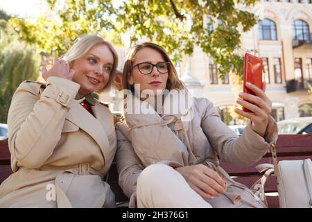 Amici femmine maturi che prendono selfie su smartphone, seduti nel parco Foto Stock