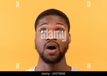 Notizie incredibili. Ritratto di uomo nero che apre la bocca e gli occhi in shock, guardando la fotocamera su sfondo giallo Foto Stock