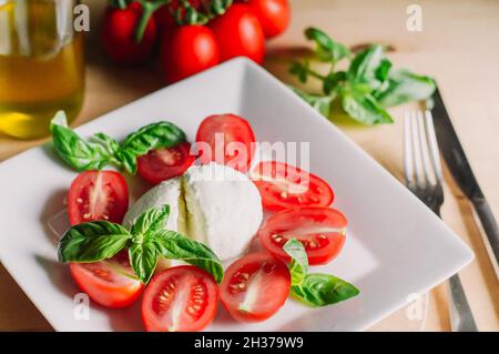 Insalata caprese con mozzarella, pomodori e basilico su un piatto bianco Foto Stock