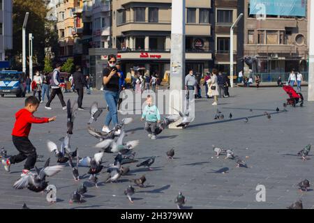 Beyoğlu,Istanbul,Turchia-Ottobre-Sabato-2021: Uccelli e bambini in corso in piazza Taksim. Donna europea che scatta foto Foto Stock