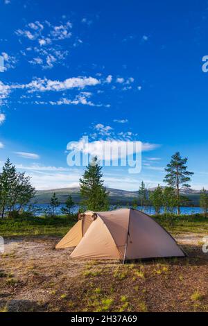 Camping tenda in campeggio panoramico su una riva del lago con la catena montuosa in background - concetto di campeggio selvaggio Foto Stock