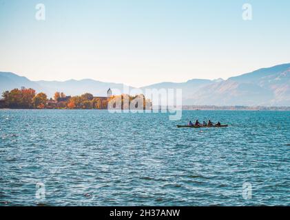 Un equipaggio di cinque skiff fila sul lago Chiemsee in una chiara mattinata autunnale Foto Stock