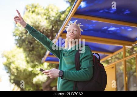 Albino afroamericano uomo con dreadlock ondeggiante con smartphone Foto Stock