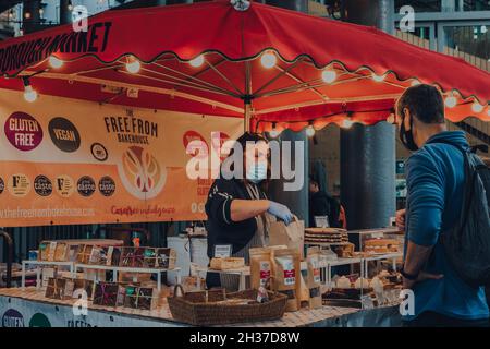 Londra, Regno Unito - 17 ottobre 2021: Venditore e cliente presso uno stallo The Free from Bakehouse nel Borough Market, uno dei più grandi e più antichi mercati alimentari in Foto Stock