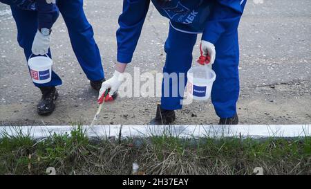 Persone che lavorano a mano indossando guanti bianchi e verniciate con una spazzola di vernice sui bordi. Clip. Lavoratori in forma dipinta Foto Stock