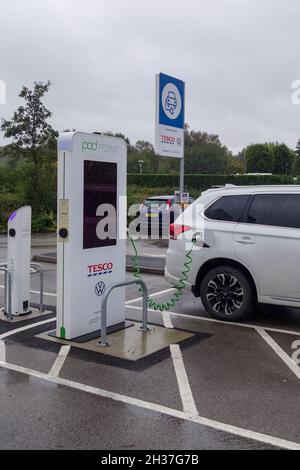 Un punto di ricarica per veicoli elettrici o veicoli elettrici Pod Point Volkswagen presso un parcheggio per supermercati Tesco, Kidsgrove, Stoke on Trent, Staffordshire, Inghilterra, REGNO UNITO Foto Stock