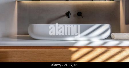 Bagno moderno lavandino su banco di marmo bianco, rubinetti neri su parete grigia, luce lineare a LED. Lavello rotondo e dettaglio rubinetti, interno minimal de Foto Stock