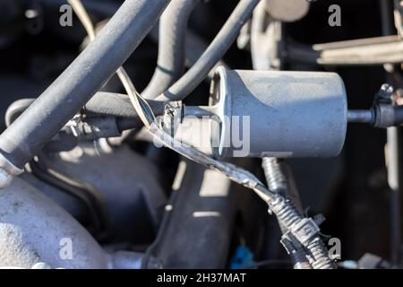 Filtro carburante installato in un'auto con una tubazione carburante collegata sotto il cofano aperto. Elemento filtrante nella tubazione carburante che cattura le particelle di sporcizia e. Foto Stock