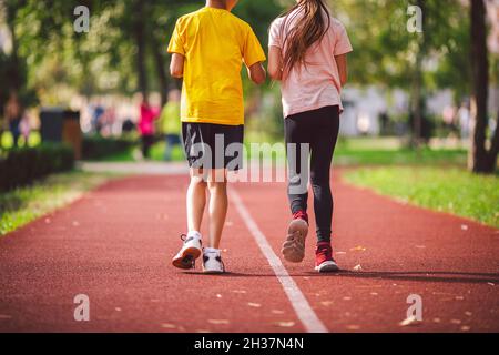 Il tema è lo sport, lo sviluppo fisico, la formazione atletica per gli scolari nelle lezioni di educazione fisica. Primo piano delle gambe due bambini ragazzo e ragazza Foto Stock