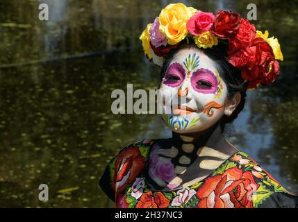 Una ragazza con il suo volto dipinto come Catrina e vestito con un abito tradizionale da Oaxaca stato pone per le foto su una barca Trajinera contiene un cestino con fiori marigoliti nel fiume Xochimilco come parte della Giornata messicana delle tradizioni morte. Il 15 ottobre 2021 a Città del Messico, Messico. (Foto di Aidee Martinez/ Eyepix Group) Foto Stock