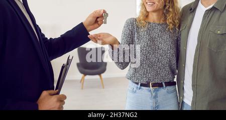 Banner con agente immobiliare o immobiliare che dà le chiavi a casa nuova per coppia felice Foto Stock