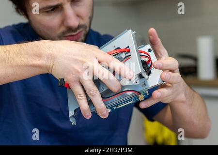 Il giovane uomo assembla i componenti elettronici del computer con le proprie mani. Hobby, tecnico, assemblaggio fai-da-te e invenzione della tecnologia Foto Stock