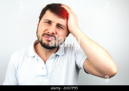 Bell'uomo bearded che tiene la testa con la sua mano e che soffre di mal di testa o di emicrania su sfondo bianco Foto Stock