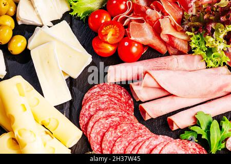Salumi, antipasti con assortimento di salumi, formaggi, camembert e olive su tavola di legno. Vari tipi di carne e salsicce su legno Foto Stock