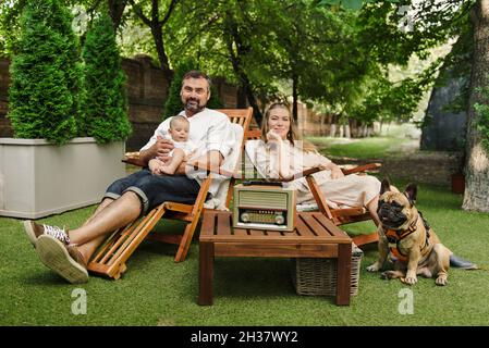 Famiglia con bambino ragazzo e cane trascorrere il tempo felice insieme fuori sulla sedia a sdraio, stile di vita Foto Stock