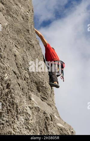Giovane uomo sportivo che arrampica parete rocciosa naturale alta a Kalnik, Croazia Foto Stock