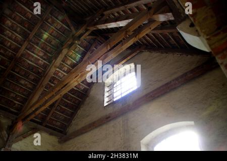 Mansarda dimenticata. La luce del sole splende da una finestra in un vecchio edificio. Interni abbandonati con travi in legno. Foto Stock