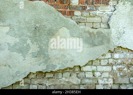 Vecchio brickwall intonacato grigio con pezzi di stucco scheggiato. Grunge muro di mattoni rosso e bianco con fondo di superficie danneggiato Foto Stock