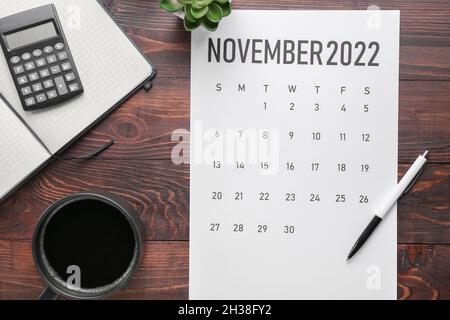 Pagina del calendario di novembre 2022, tazza di caffè e cancelleria su sfondo di legno scuro. Black Friday Foto Stock