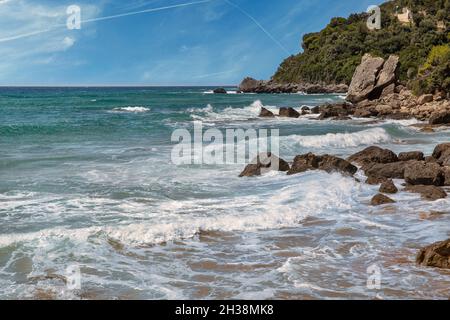 Bella vista panoramica onde di mare che si infrangono su rocce con spruzzi d'acqua. Mirtiotissa, isola di Corfù, Grecia. Foto Stock