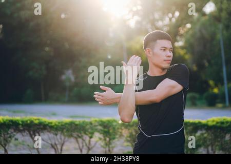 Giovane pareggiatore maschio che si riscalda allungando le braccia e la parte superiore del corpo b Foto Stock