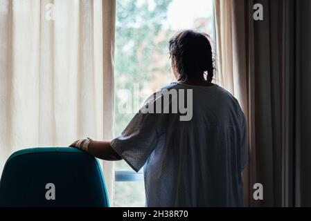 Paziente giovane che guarda fuori dalla finestra di un ospedale. Foto Stock