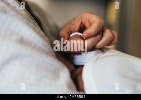 Mano della madre che tiene la mano del neonato durante l'allattamento al seno. Foto Stock