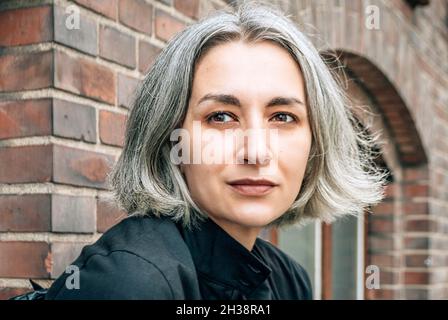 Ritratto di donna grigio-capelli su mattone rosso edificio backgroung Foto Stock