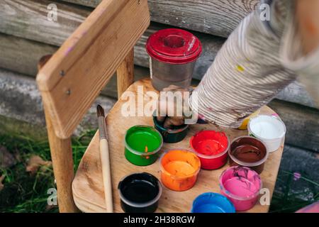 La bambina sceglie un colore per dipingere con le dita. Le mani si avvicinano. Il concetto di creatività dei bambini Foto Stock