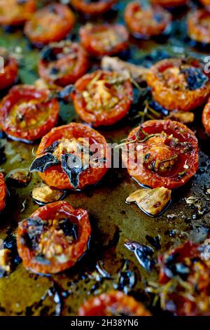 Pomodori ciliegini arrostiti in padella piatta. Cosparsa di olio d'oliva e timo, con sale marino e pepe Foto Stock