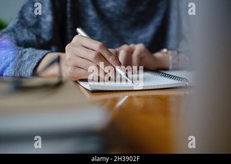 Giovane università femminile prendendo appunti e utilizzando l'evidenziatore. Studente focalizzato in aula online. Concetto di istruzione autentica. Foto Stock