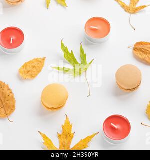 Composizione autunnale. Foglie, candele e macaroni gialli su sfondo bianco. Autunno, autunno, Halloween concetto. Disposizione piatta, vista dall'alto, immagini luminose Foto Stock