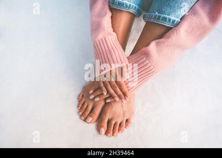 Donna elegante che mostra le sue mani e piedi con bella manicure e pedicure. Sfondo bianco con spazio di copia Foto Stock