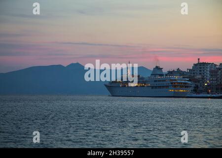 Сruise Liner al porto ща di Saranda, Albania in serata con le luci accese, fumo dalle tubazioni. Foto Stock