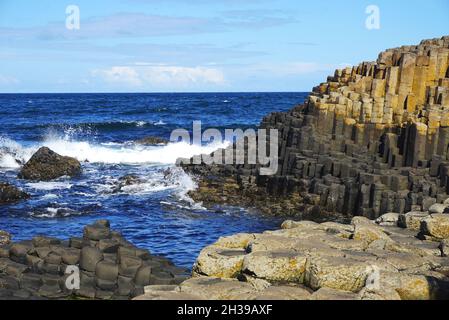 Le onde si infrangono a terra sulle formazioni rocciose vulcaniche di basalto naturale del Selciato del Gigante, nella contea di Antrim, sulla costa settentrionale dell'Irlanda del Nord. Foto Stock