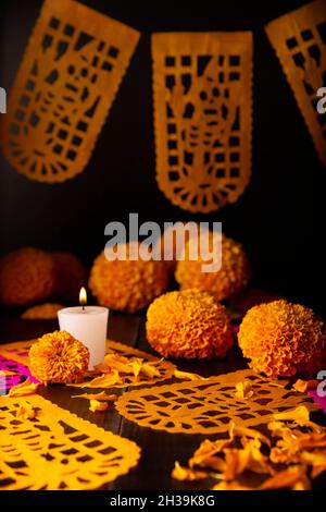 Candela con fiori d'arancio Cempasuchil o Marigold. (Tagetes erecta) e Papel Picado. Decorazione tradizionalmente utilizzata negli altari per la celebrazione di Foto Stock