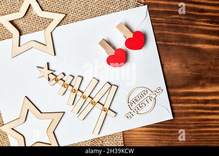 Nuovo anno Flatlay su tela e sfondo in legno fatto di busta, albero di Natale, stelle e clothespins con cuori. Primo piano Foto Stock