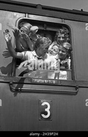 BDM Mädel winken aus ihrem Zugabteilfenster bei der Fahrt in die Ferien, Deutschland 1930er Jahre. Le ragazze della BDM che si acclamano dalla finestra del loro treno che le porta alle loro vacanze, la Germania anni trenta. Foto Stock