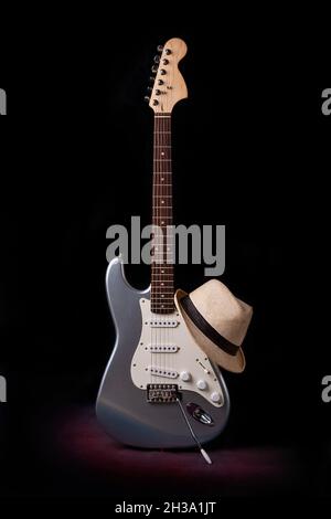 Chitarra elettrica argentata con cappello isolato su sfondo nero Foto Stock