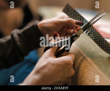 il processo di taglio della carta con le forbici. forbici nelle mani femminili primo piano Foto Stock