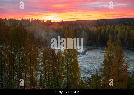Il sole che sorge sopra l'orizzonte e un fiume con nebbia da una rapida immagine, dal Vasternorrland Svezia. Foto Stock