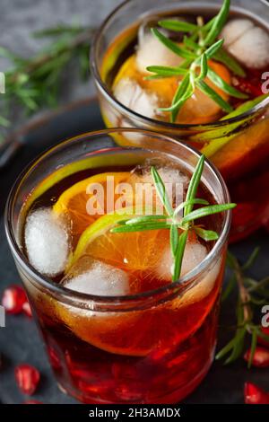 Cocktail di melograno decorato con lime, rosmarino e ghiaccio, bevanda fredda Foto Stock