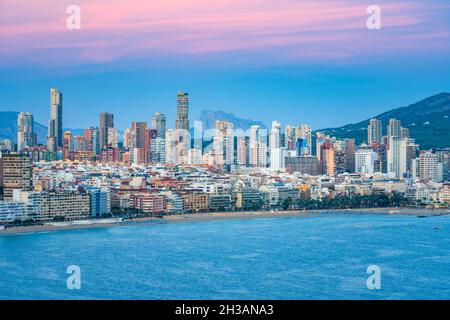 Vista dello skyline di Benidorm, fronte mare, Levante Beach e Ifach Rock sullo sfondo al crepuscolo. Foto Stock