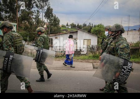 Pujili, Ecuador. 26 ottobre 2021. Una donna della comunità Pujili attraversa i sentieri con una squadra di forze speciali dell'Esercito Equadoriano durante le manifestazioni nella provincia di Cotopaxi in Ecuador 26 ottobre 2021. Le comunità indigene chiudono le strade principali in tutto il paese a causa dello sciopero nazionale chiamato dal movimento indigeno CONAIE in collaborazione con i sindacati e altre organizzazioni sociali che richiedono che il prezzo del carburante nel paese sia abbassato. (Foto di Juan Diego Montenegro/Sipa USA) Credit: Sipa USA/Alamy Live News Foto Stock