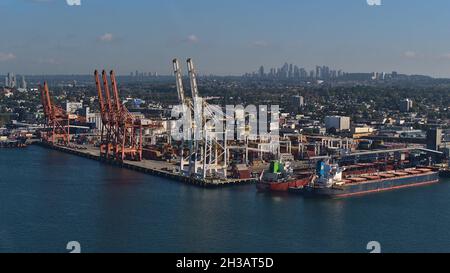 Vista aerea del terminal container di Vancouver con gru e navi portarinfuse e grattacieli di Burnaby in background in giornata di sole. Foto Stock